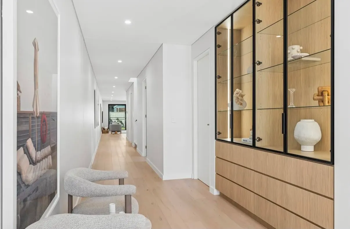 Hallway display cabinet with black-framed glass doors, lit glass shelves and timber-look drawers below